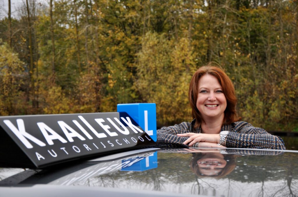 Manon hangt op het dak van lesauto